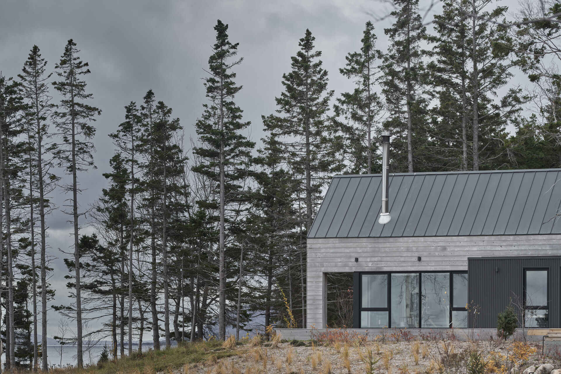 A collection of five wood-clad prefab cabins on the coast designed for outdoor living and hosting.